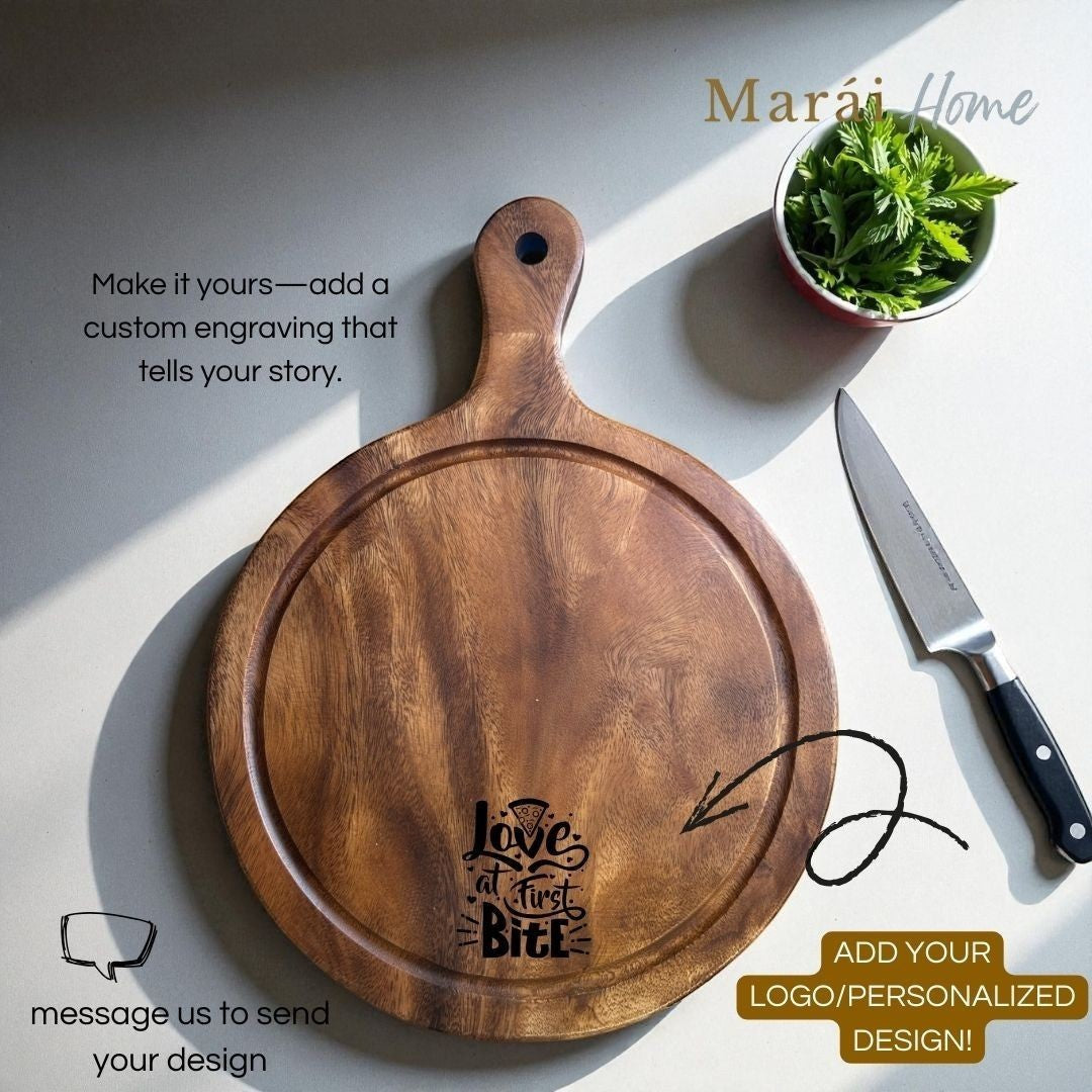 Marai Home round acacia wood pizza board with groove and handle, engraved with "love at first bite" text.