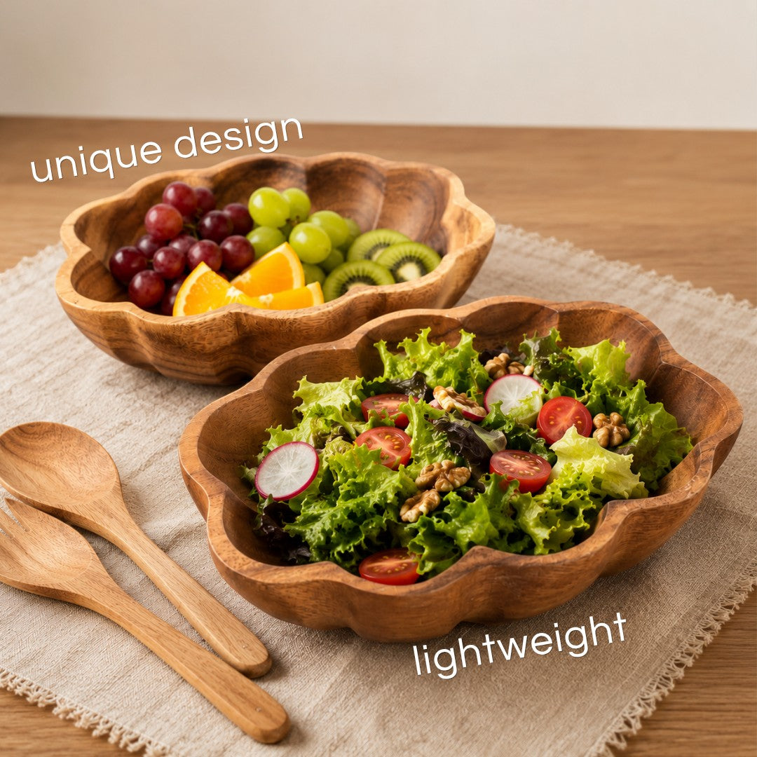 Marai Home handcrafted acacia wood scallop bowls filled with fresh salad and fruit on a linen placemat with wooden spoons